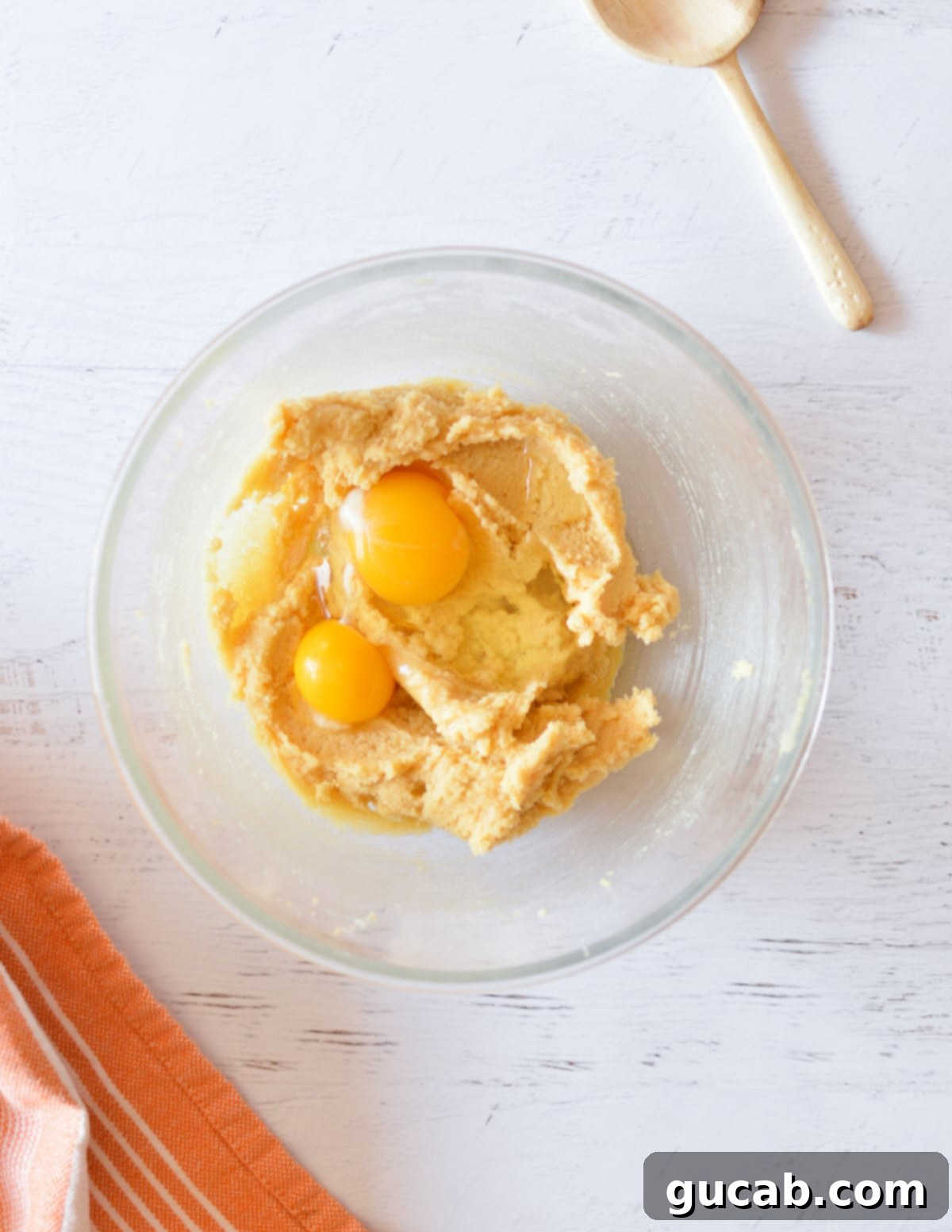 Creamed butter and sugar mixture in a bowl, with the egg and vanilla extract added on top, ready for mixing.