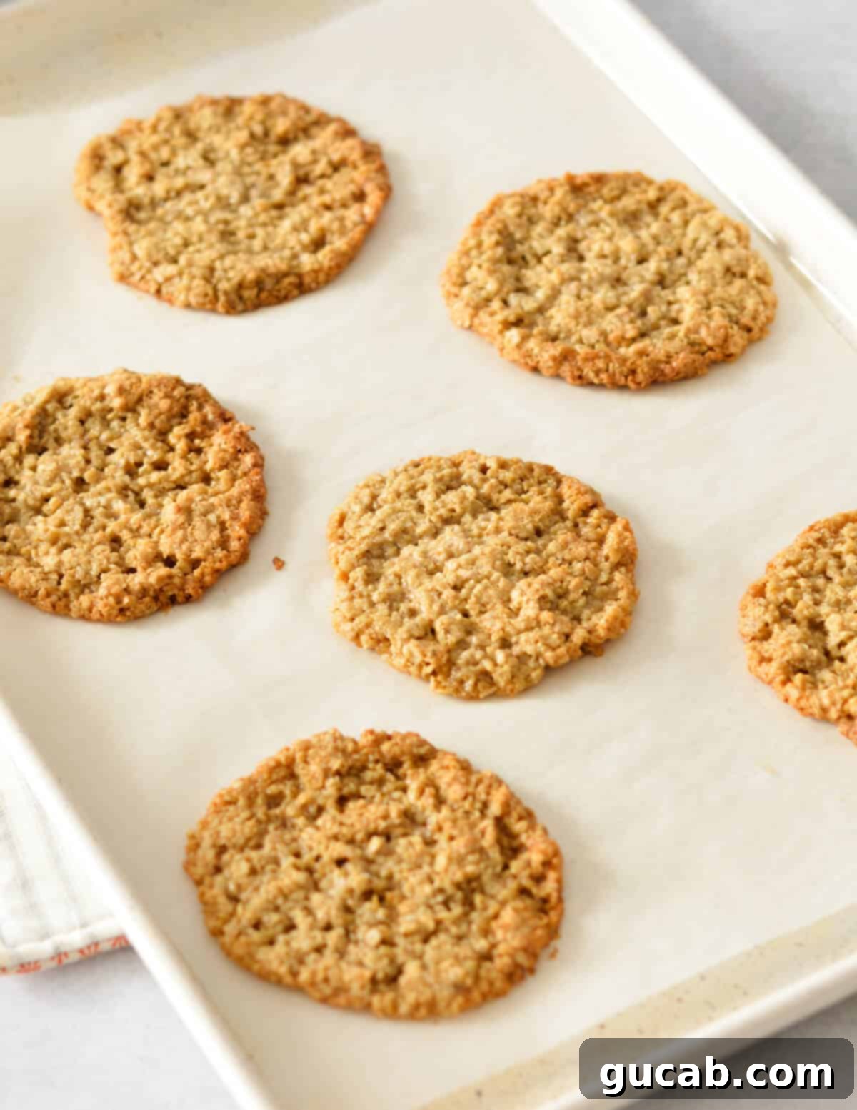 Gluten-Free Oatmeal Cookies 12 Freshly baked flourless oatmeal cookies cooling on a sheet pan, showing their perfect golden-brown edges.