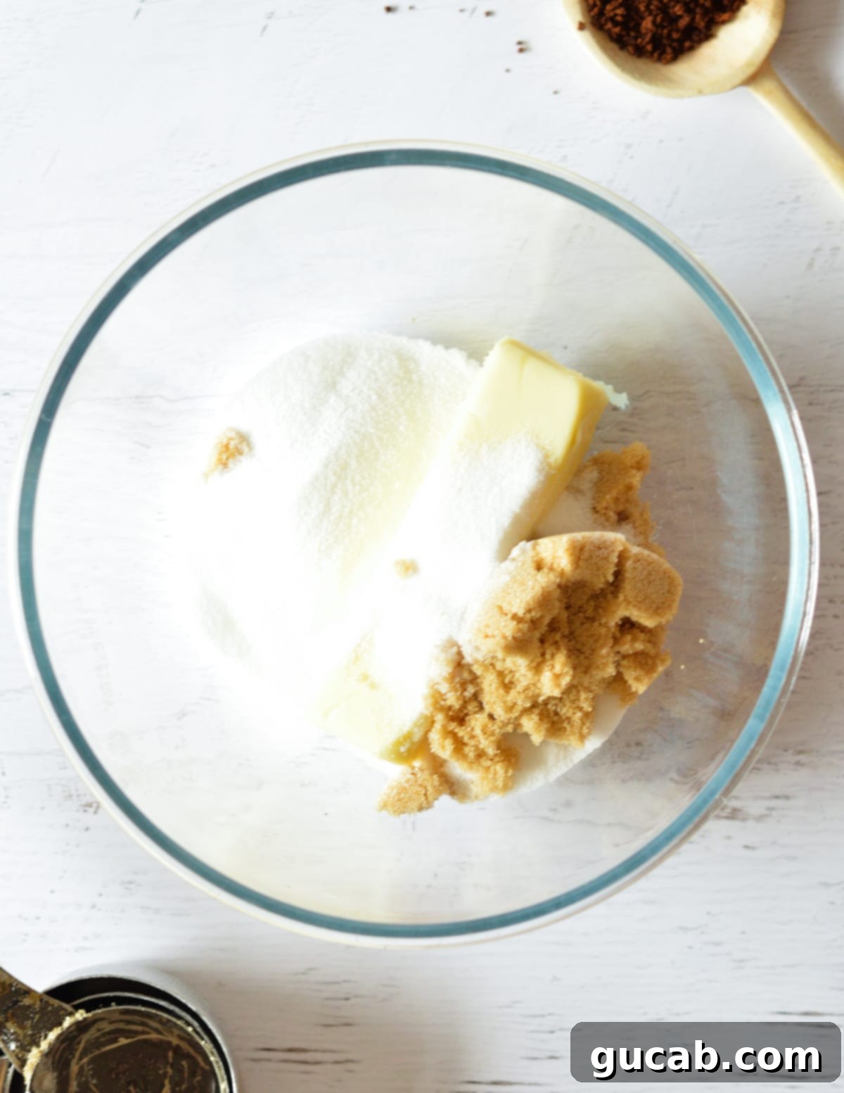 A bowl containing room-temperature butter, granulated sugar, and brown sugar, ready for creaming.