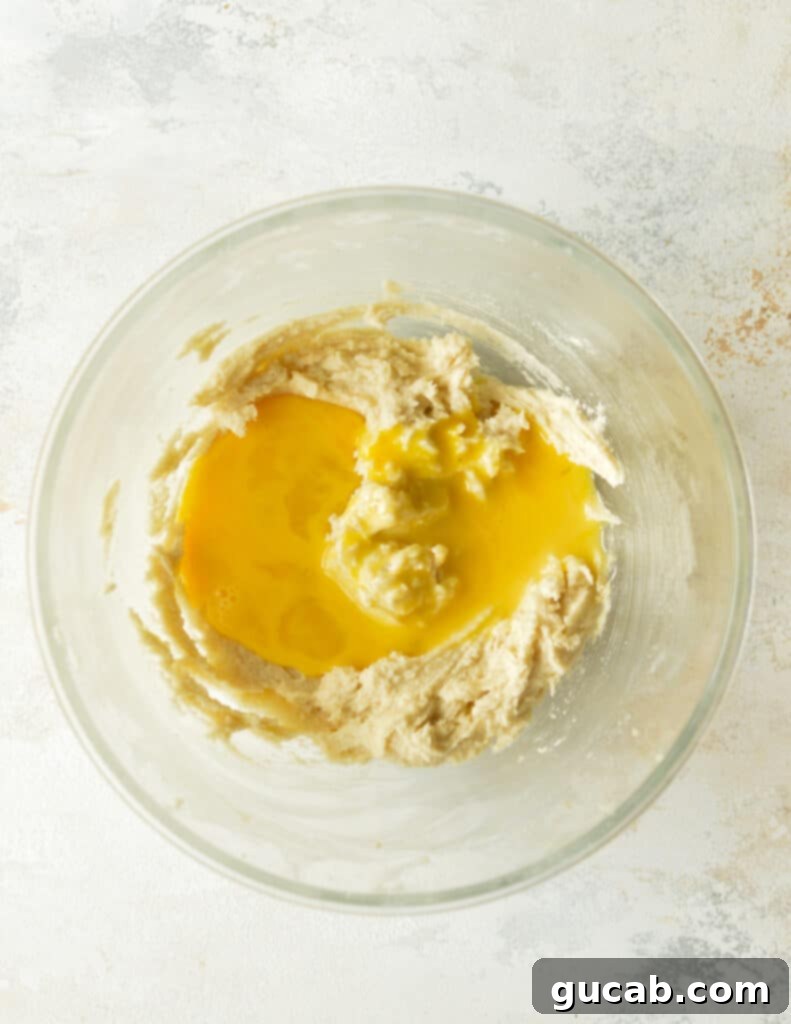 Creamed butter and sugar mixture with a single egg on top, ready to be beaten.