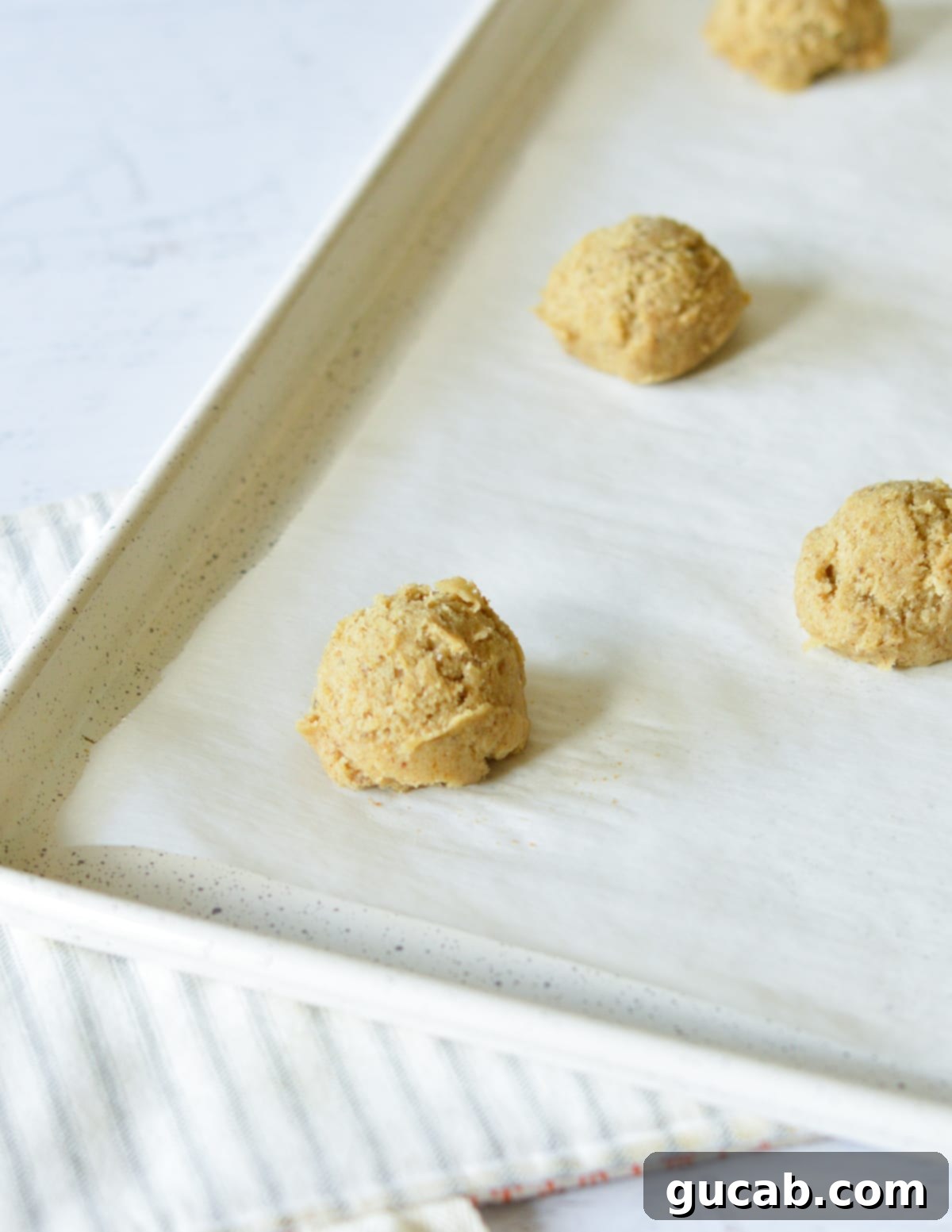 Scooped coffee cookie dough balls arranged evenly on a parchment-lined sheet pan, ready for baking.