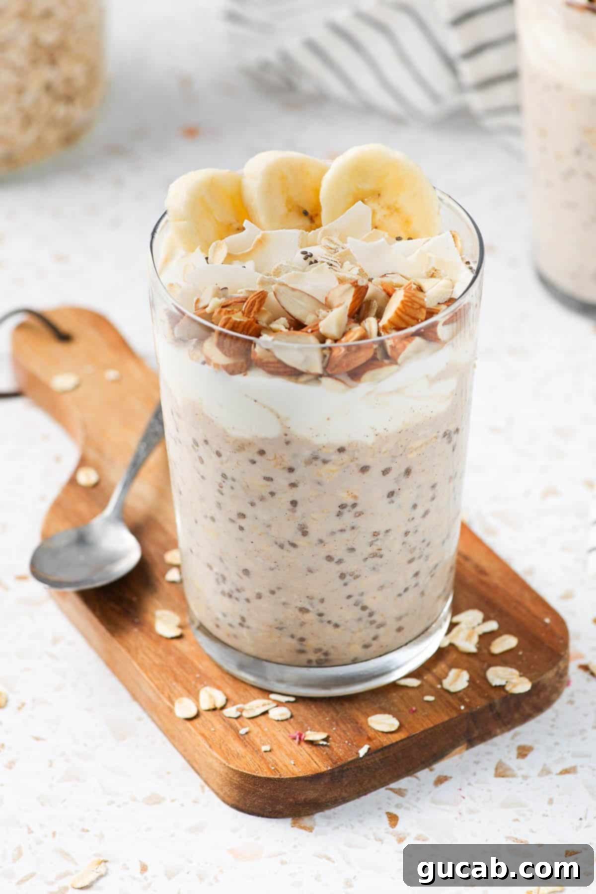 a glass of overnight oats with banana, almonds, and coconut. 