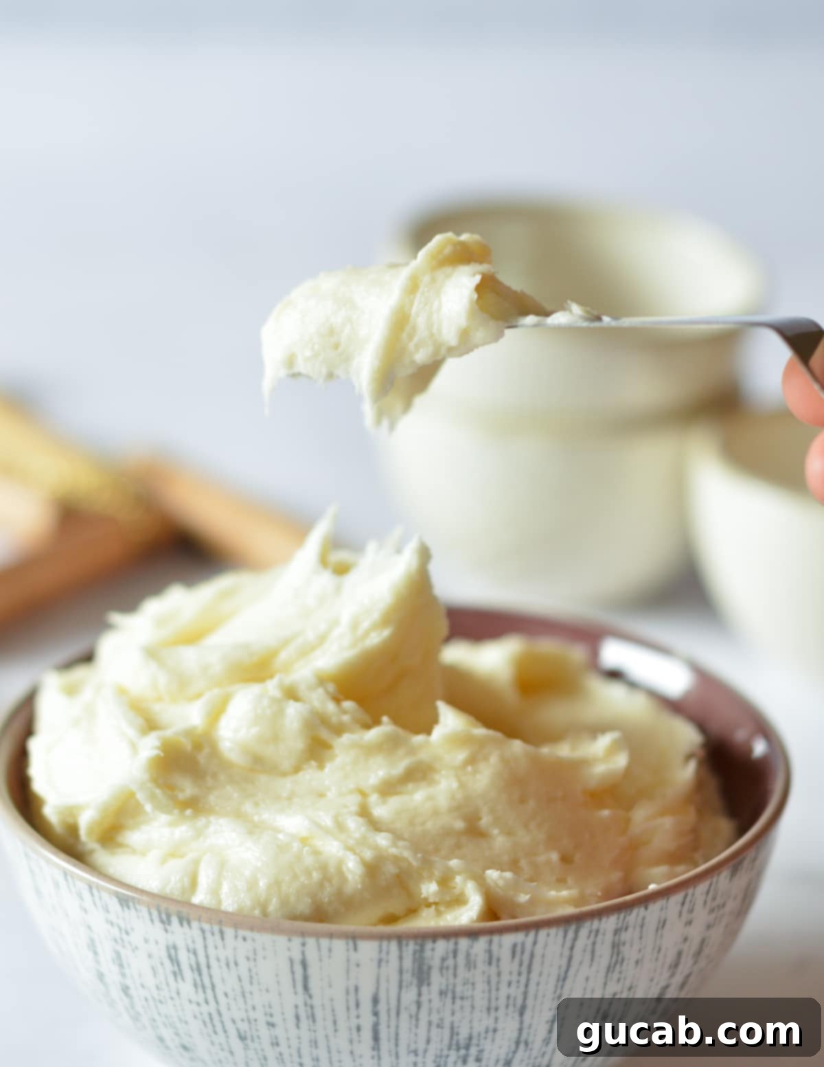 A large bowl filled with freshly made, smooth cream cheese frosting, ready for use.