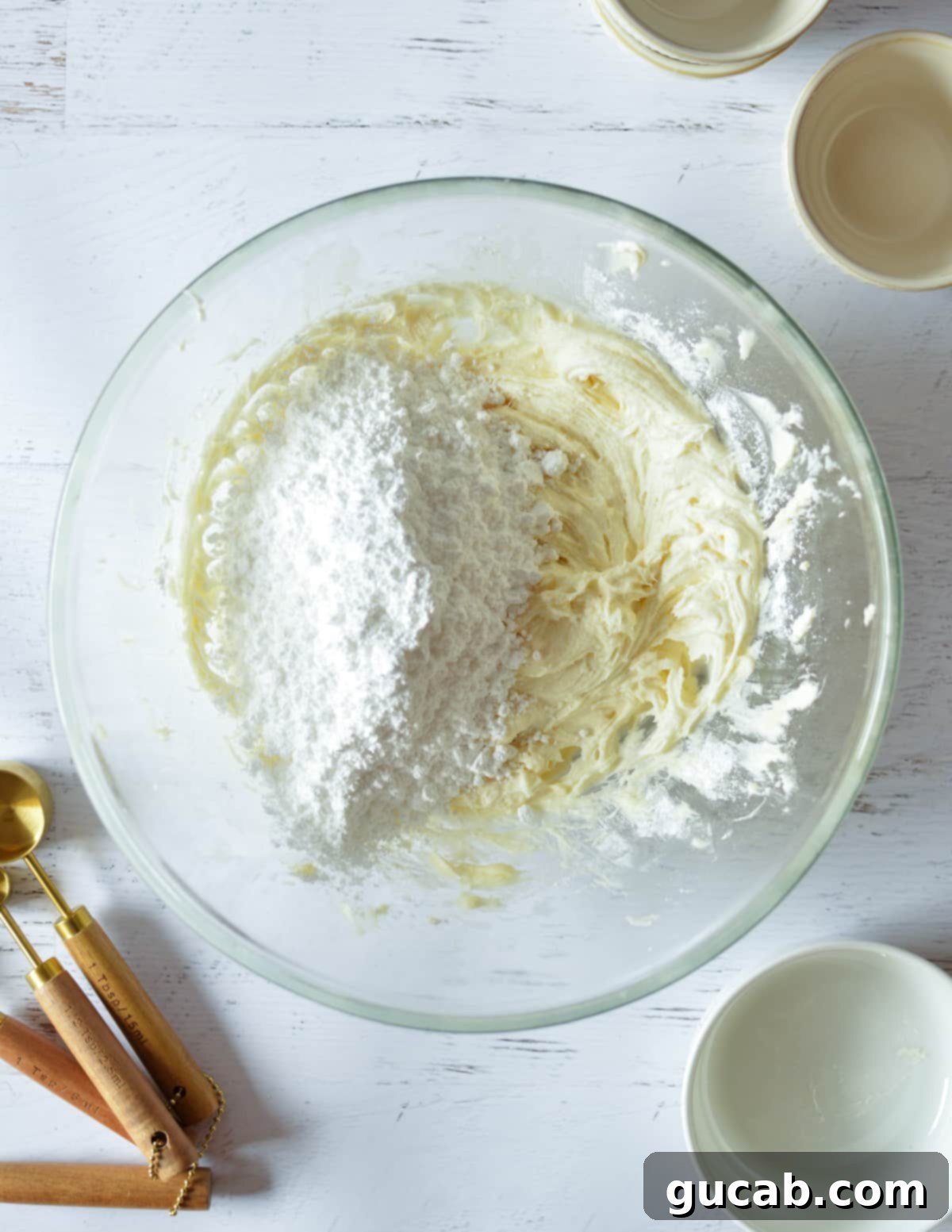The bowl with cream cheese frosting, showing the final addition of powdered sugar on top.