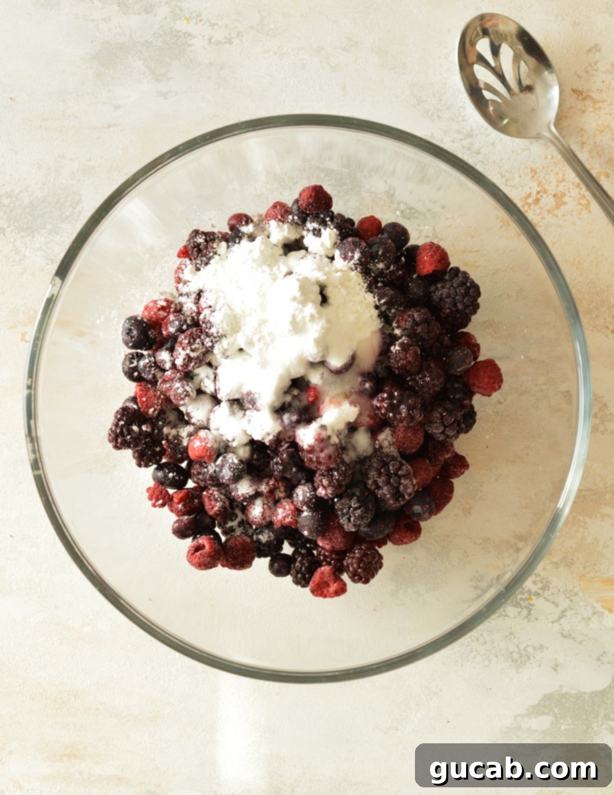 A bowl of vibrant frozen mixed berries, lightly dusted with cornstarch, ready for mixing.