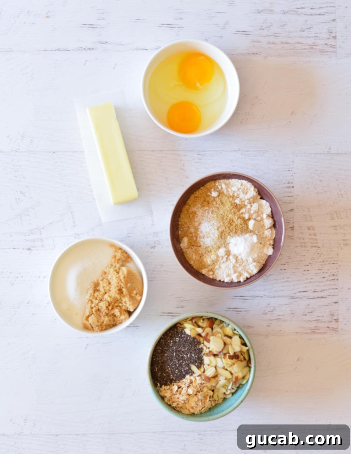 Wholesome Fiber Cookies 3 A collection of key ingredients for high fiber cookies, including unsalted butter, eggs, oat flour, flax meal, almonds, chia seeds, and sugar.