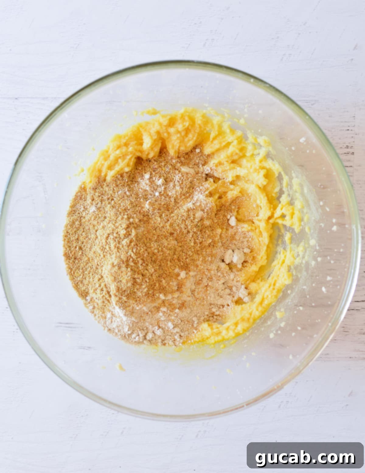 Wholesome Fiber Cookies 8 A bowl with creamed butter and sugar, topped with flax meal and oat flour, ready for mixing.