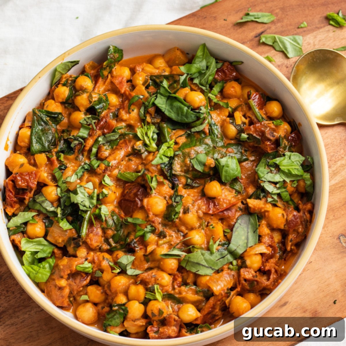 chickpeas in a sundried tomato sauce in a bowl with spinach. 