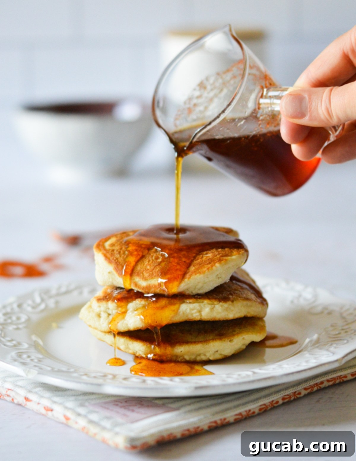 Golden pancakes generously drizzled with rich, amber spicy maple syrup, showcasing its tempting texture.