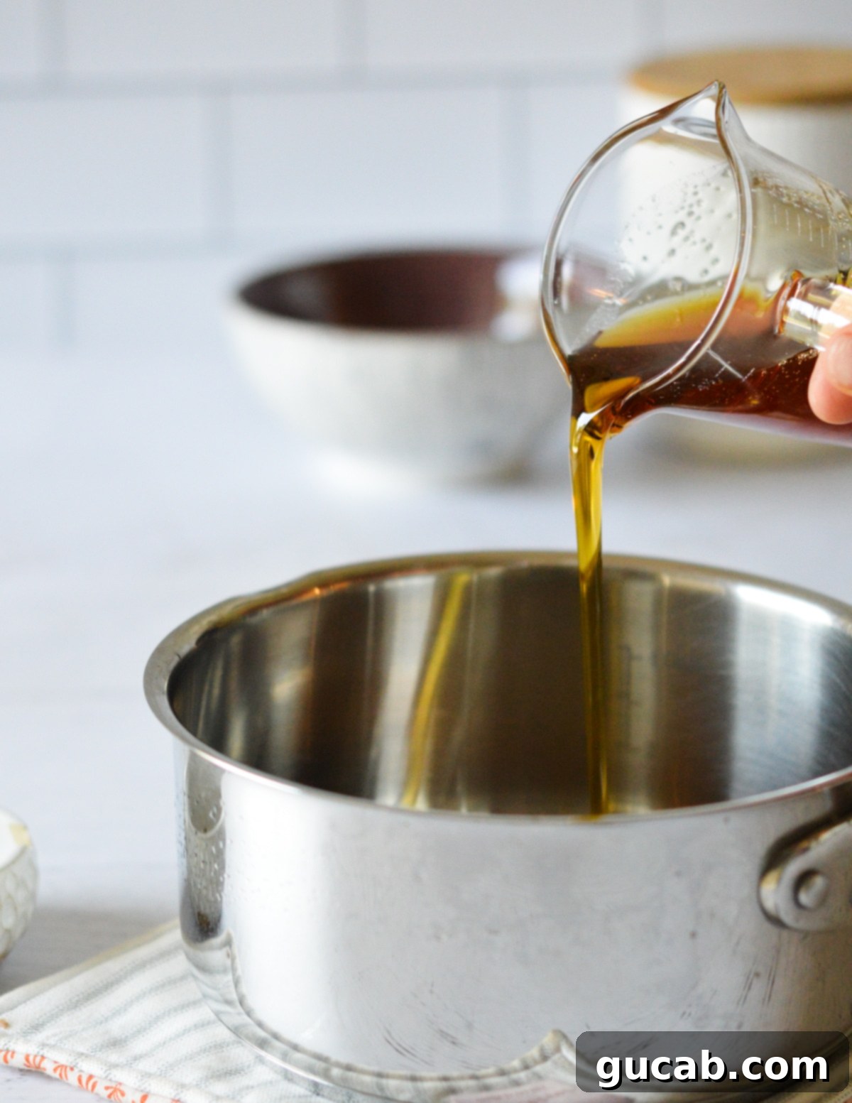 Pure maple syrup being poured into a small, gleaming saucepan, ready for infusion.