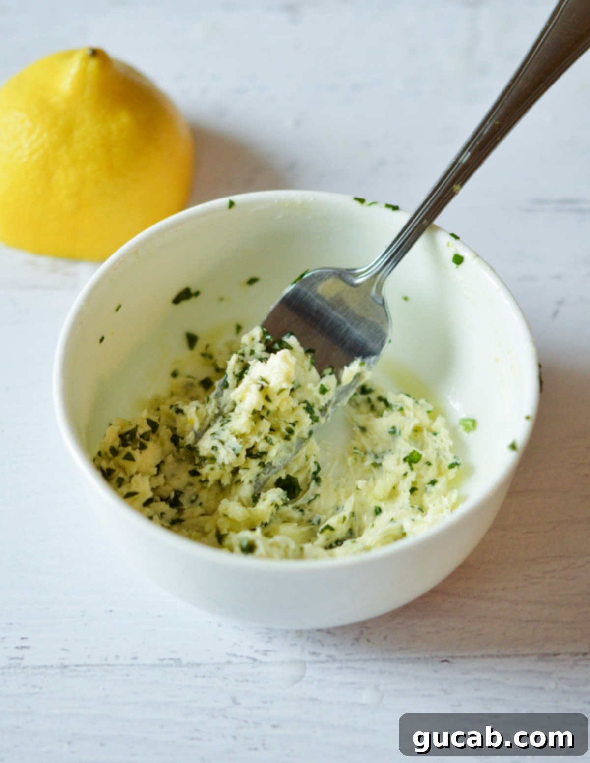 a bowl of lemon basil butter with a fork in it. 