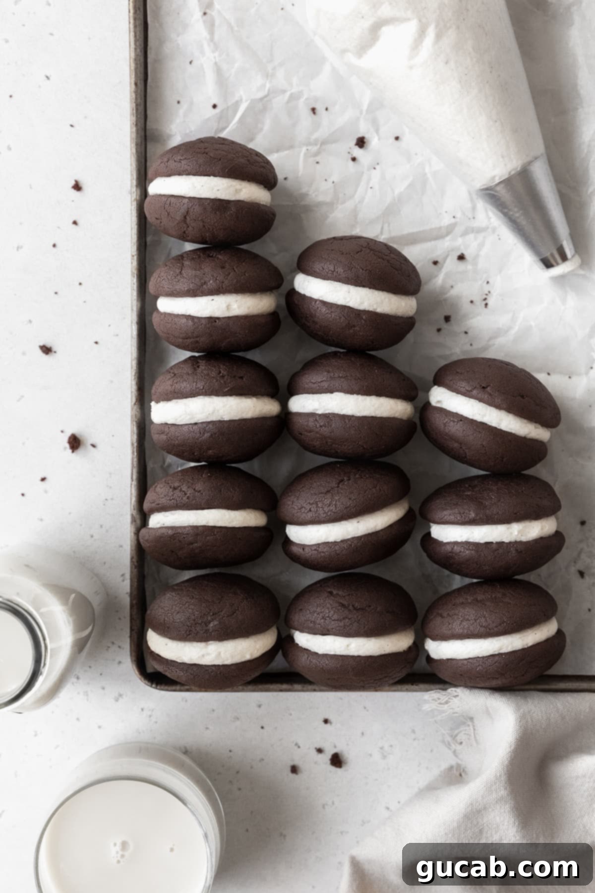 Gluten-free chocolate whoopie pies with creamy vanilla filling on a sheet pan.