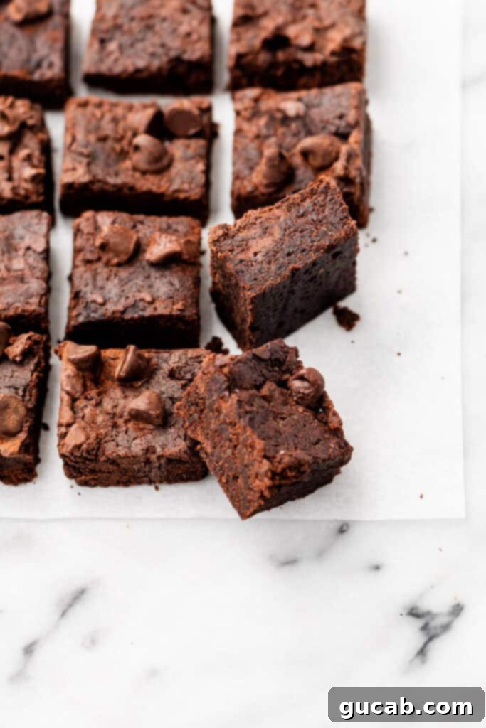 Rich, fudgy gluten-free and vegan brownies sliced on parchment paper.