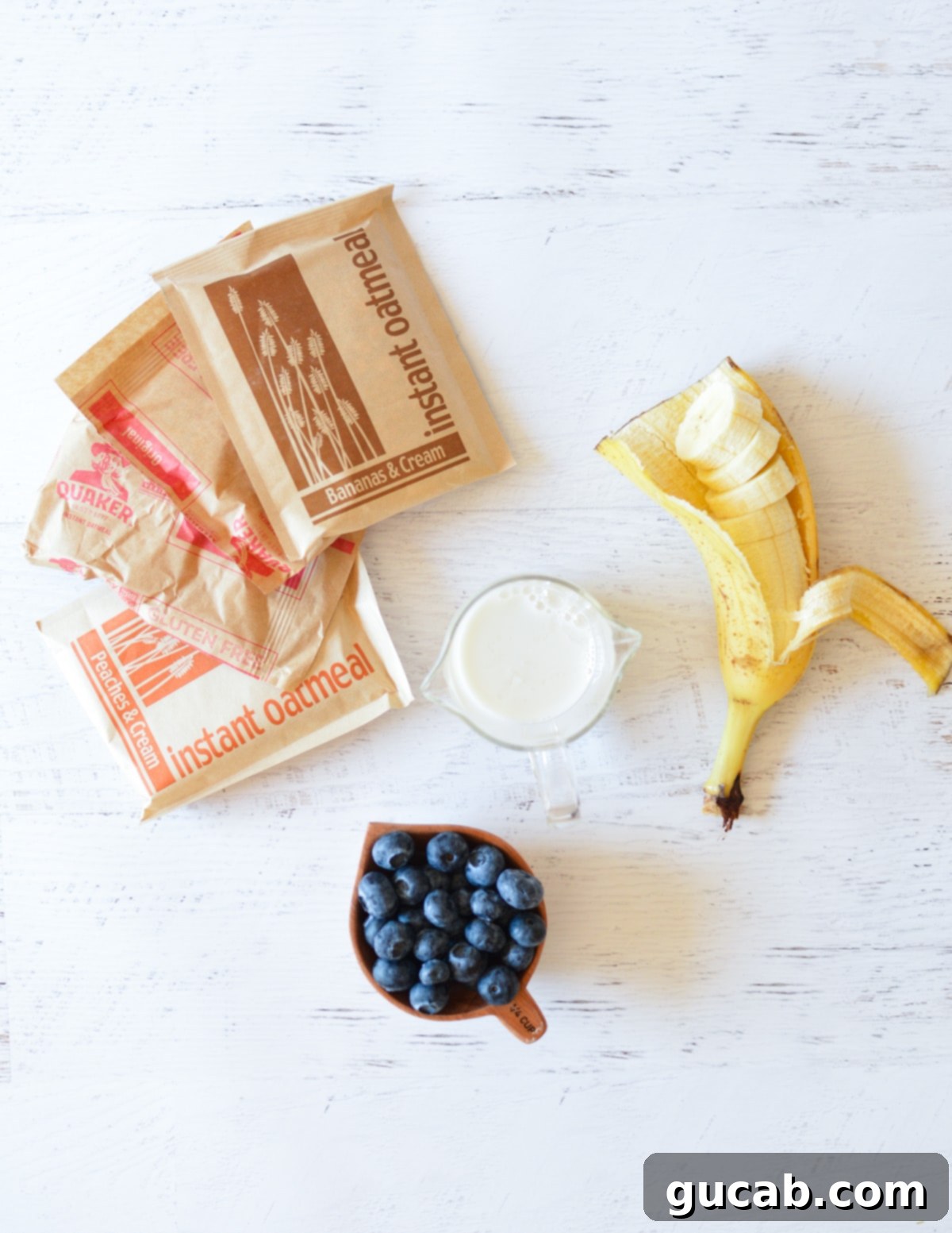 Effortless Overnight Oats Using Instant Packs 3 Key ingredients laid out: instant oatmeal packets, a carton of milk, fresh banana slices, and plump blueberries, ready for making overnight oats.