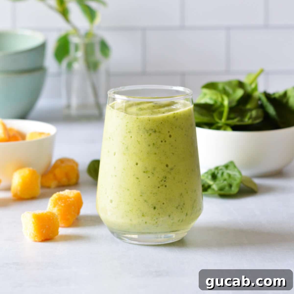Tropical Green Boost 2 A refreshing glass of pineapple spinach smoothie, garnished with a pineapple wedge.