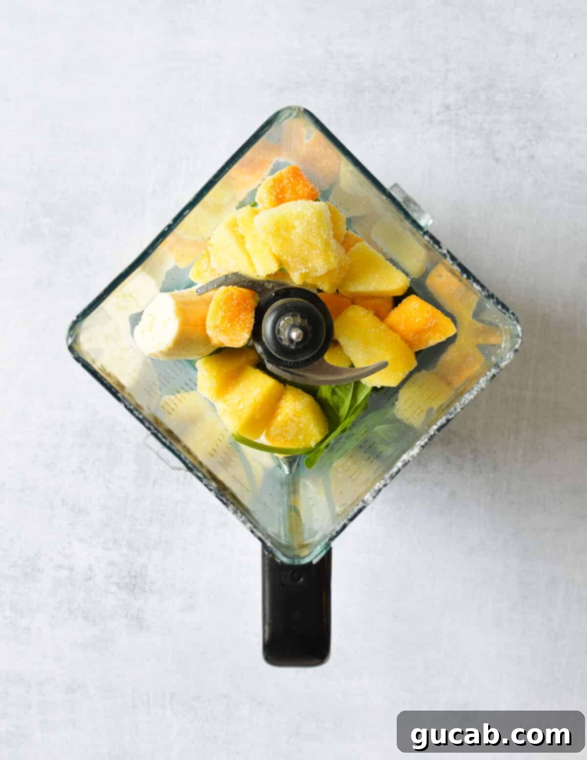 Tropical Green Boost 4 Frozen pineapple, frozen mango, spinach, and banana placed in a blender jar, ready for blending.