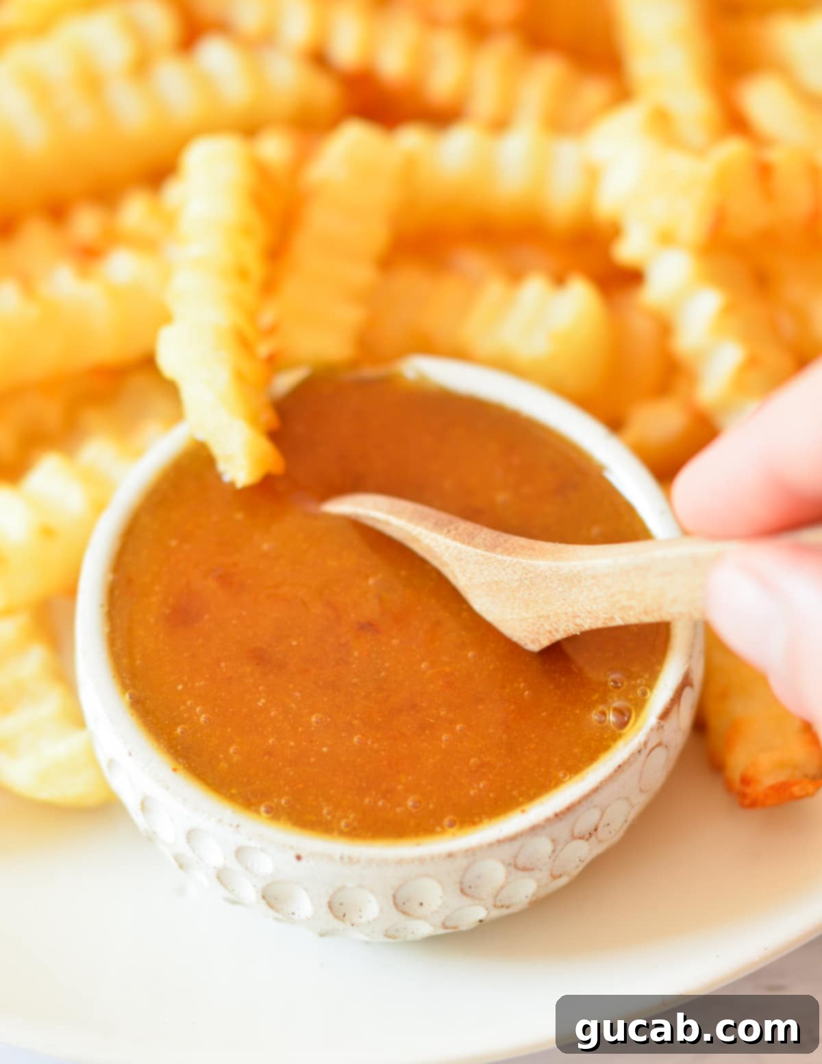 A bowl of homemade sweet and sour sauce surrounded by crispy french fries, ready for dipping.