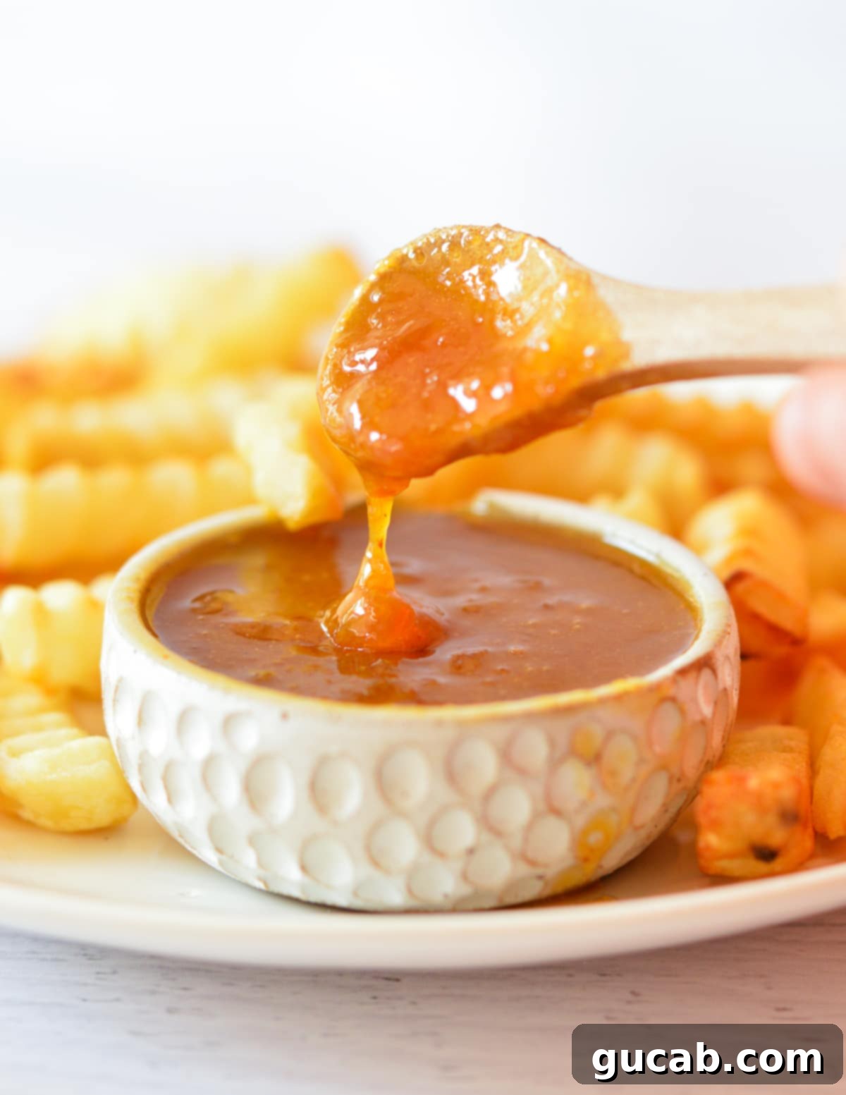 A spoonful of homemade sweet and sour sauce, showing its smooth texture and rich color.