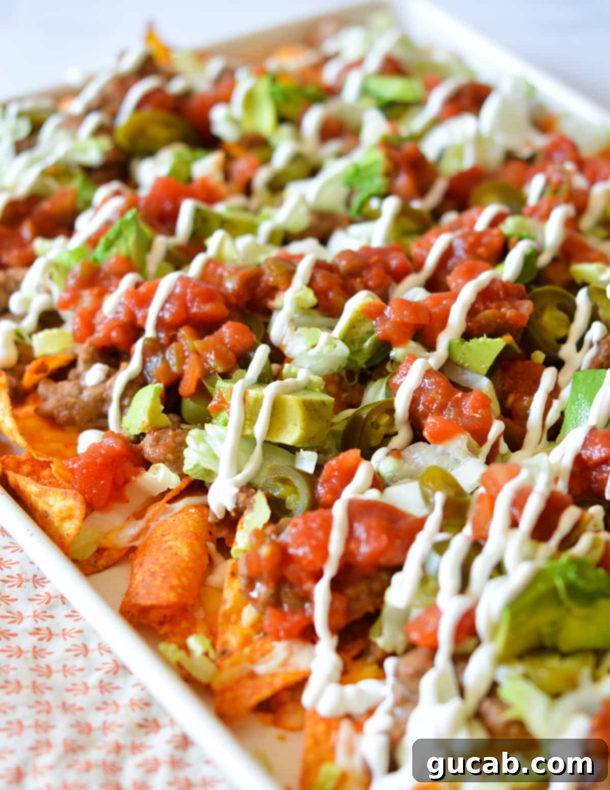 A vibrant platter of loaded Doritos nachos featuring ground beef, melted cheese, and fresh toppings like lettuce, avocado, and sour cream.