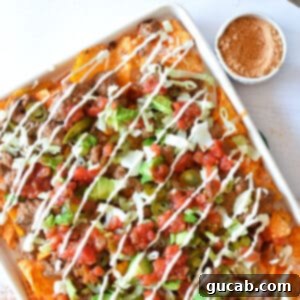 A close-up of a serving of loaded Doritos nachos with ground beef, melted cheese, and fresh toppings.