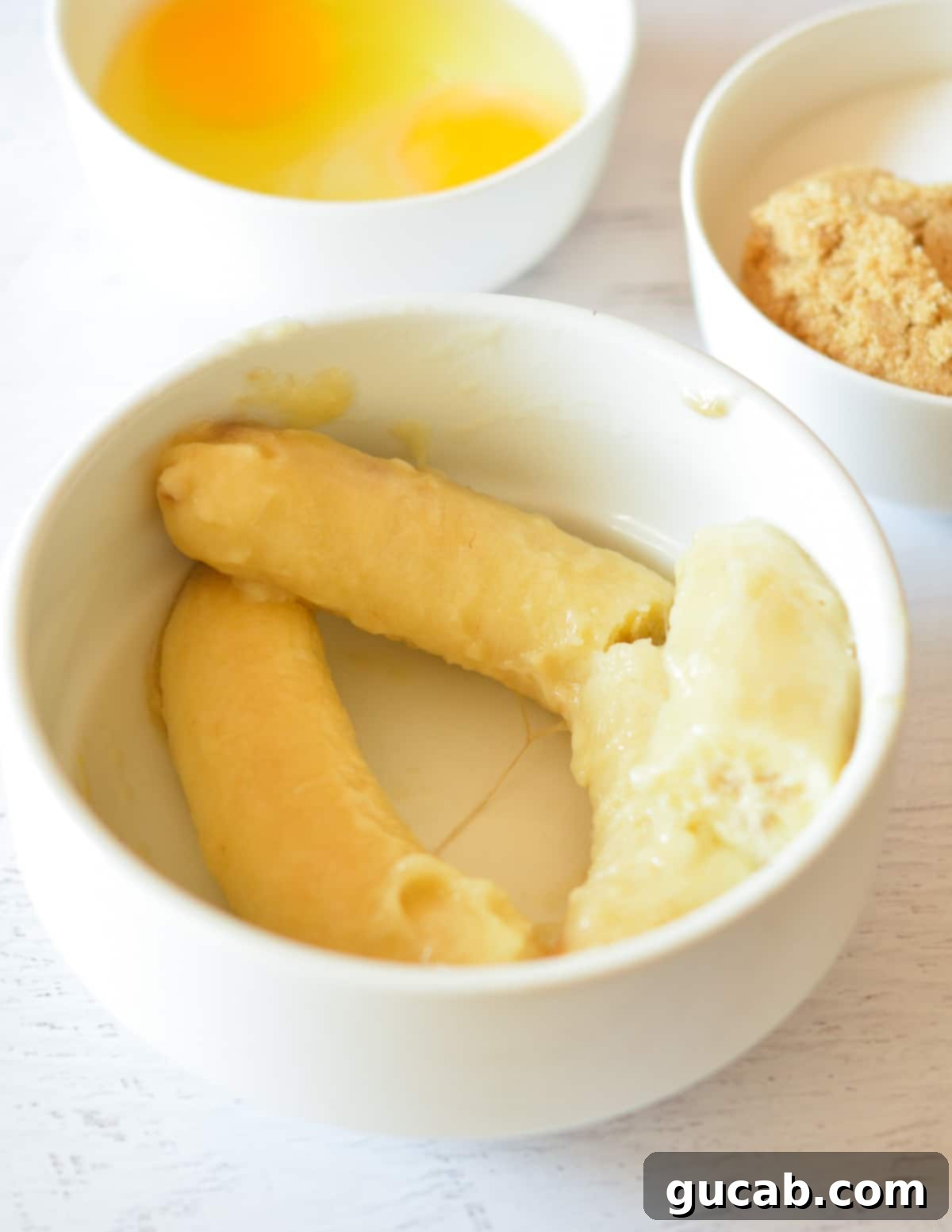 A bowl of thawed, dark bananas, ready for mashing, showing the natural liquid released during thawing.