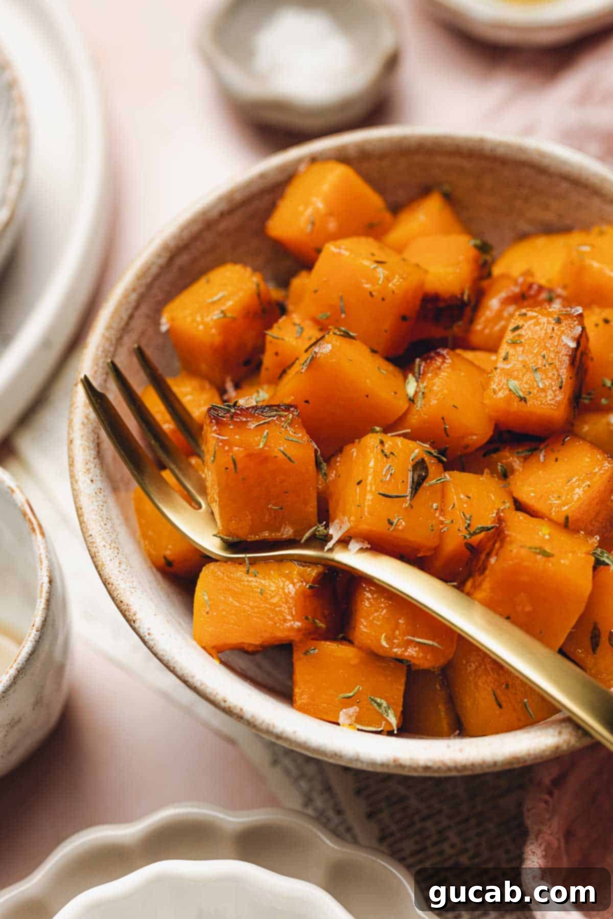 A charming bowl of perfectly sauteed butternut squash, adorned with a fork, ready to be savored as a comforting side dish.