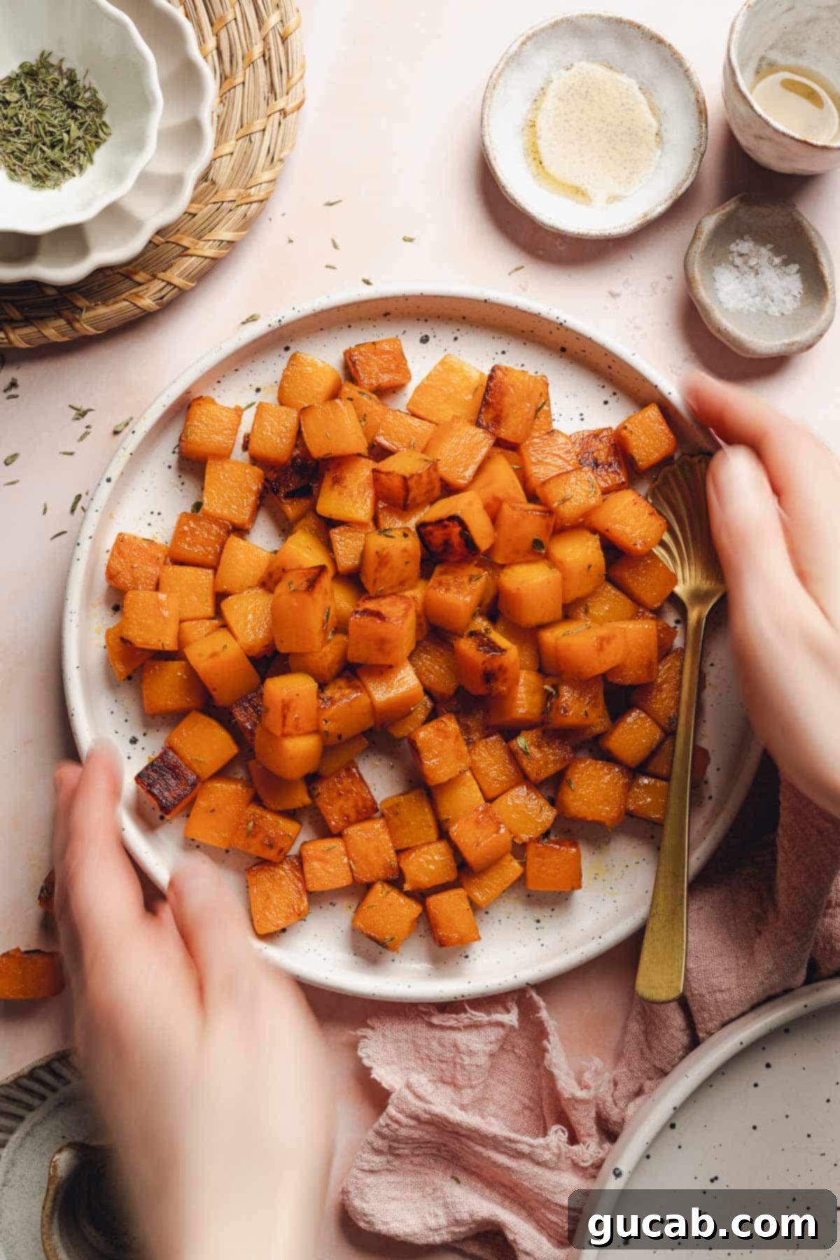 A pair of hands gently holding a plate of golden-brown caramelized butternut squash, ready to be served and enjoyed.