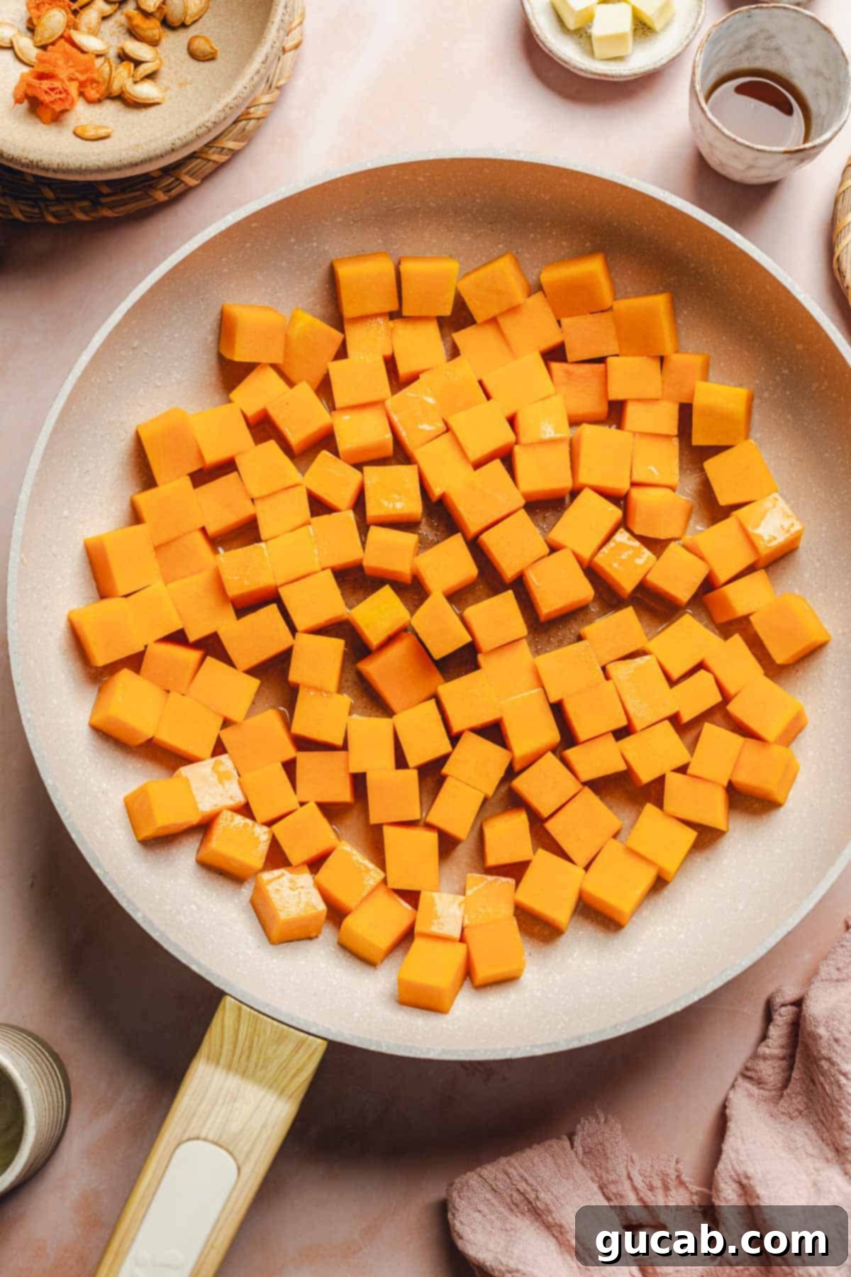Butternut squash cubes starting to soften and brown in a hot skillet with olive oil.