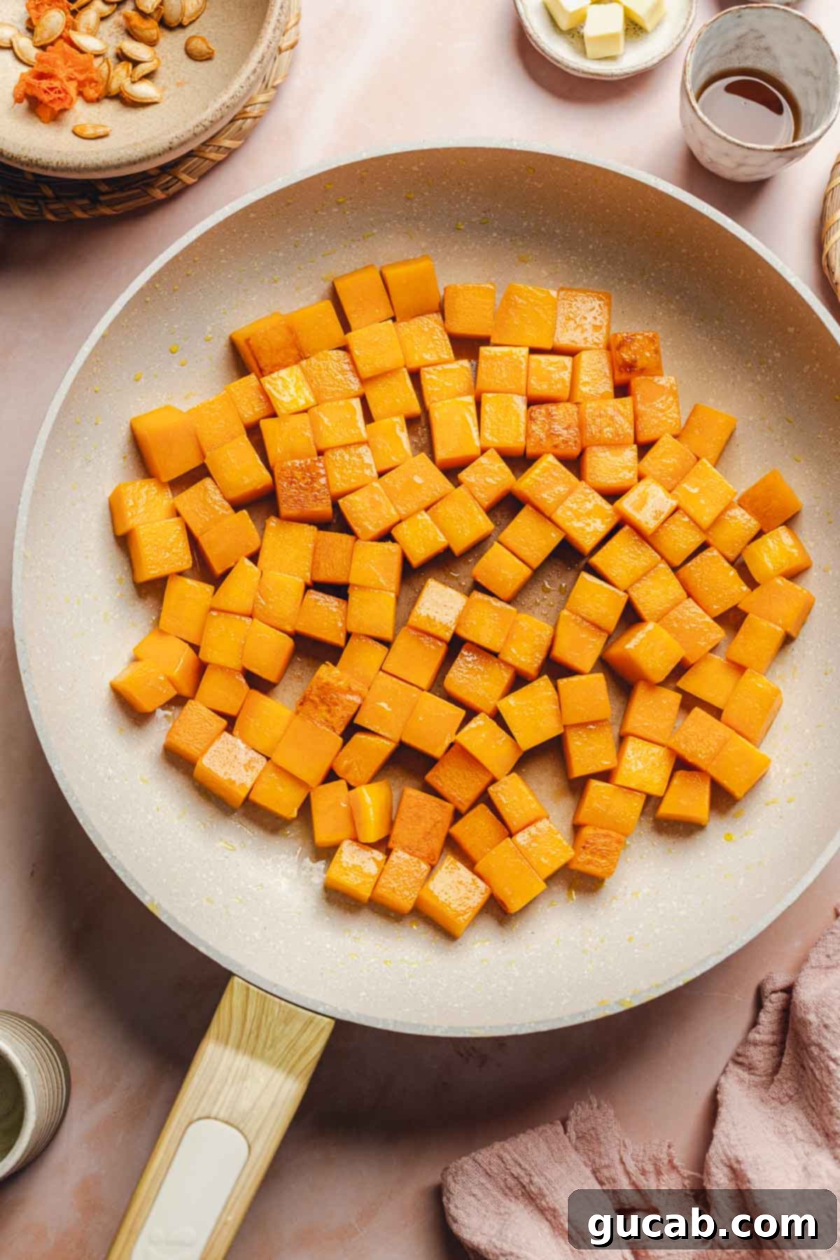 Partially sauteed butternut squash cubes in a skillet, showing early signs of caramelization and tender texture.
