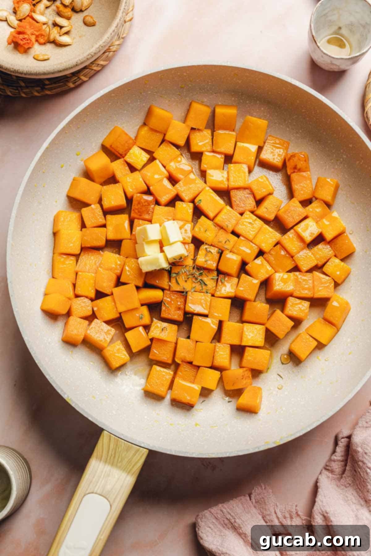 A knob of butter melting into the skillet with sauteed butternut squash, adding richness to the glaze.