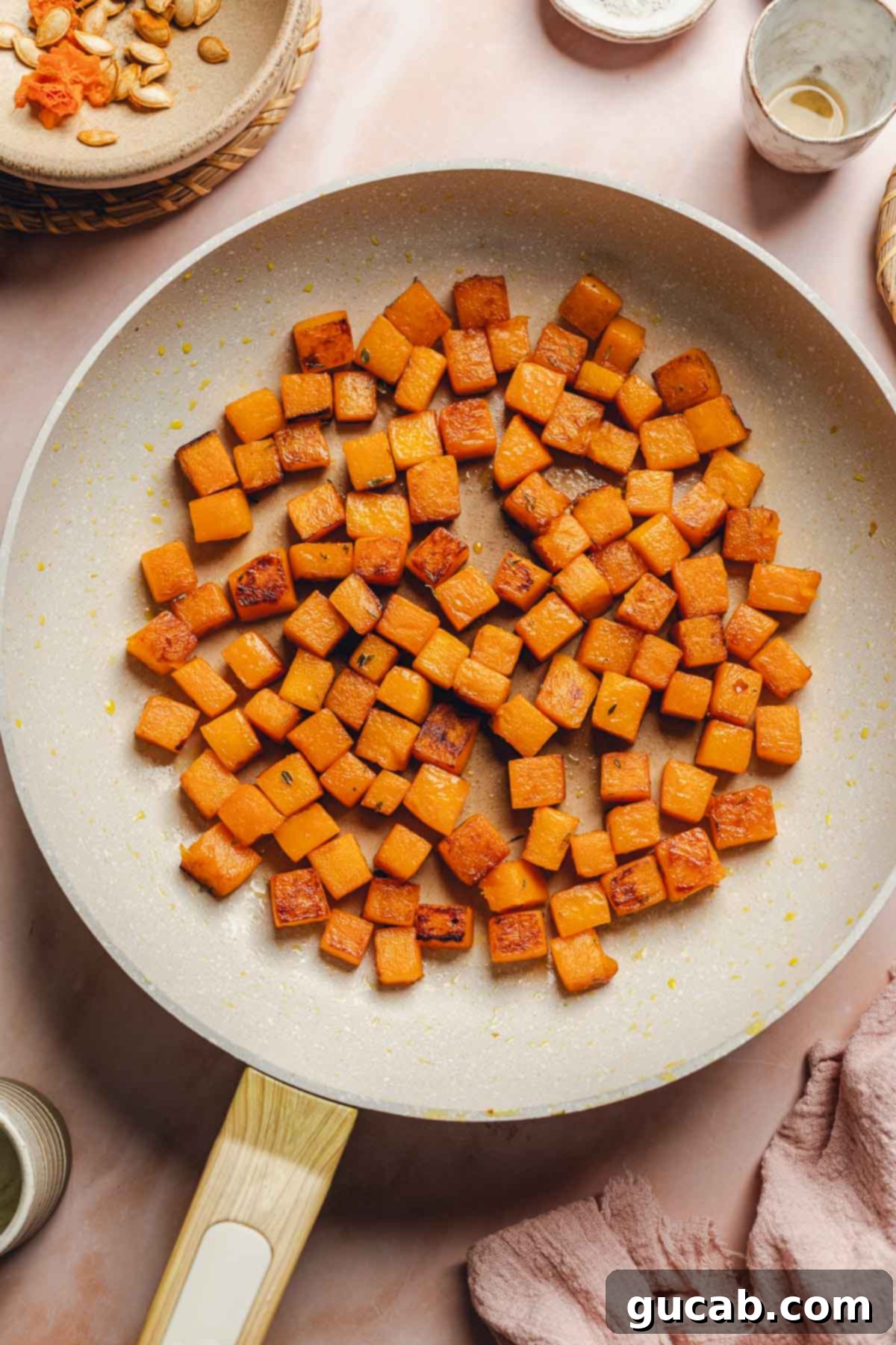 Gloriously caramelized butternut squash cubes, rich with maple butter, scattered in a skillet after being fully cooked.
