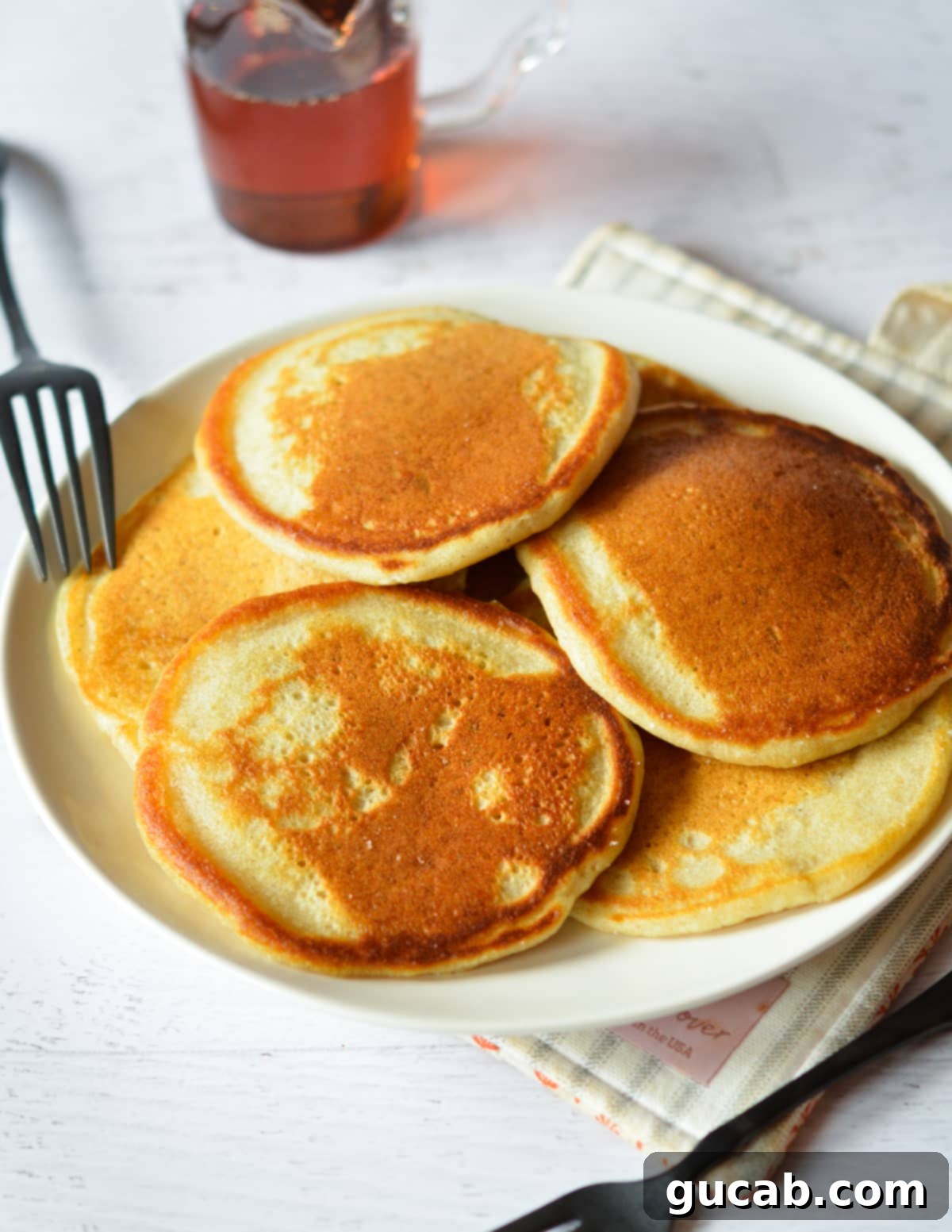 A close-up shot of a plate of perfectly golden brown pancakes, ready to be enjoyed with their crispy edges visible.