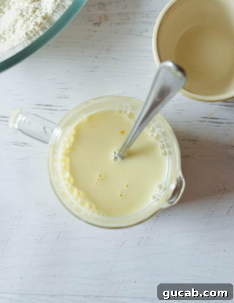 A measuring cup filled with whole milk and a large egg, being whisked with a fork.