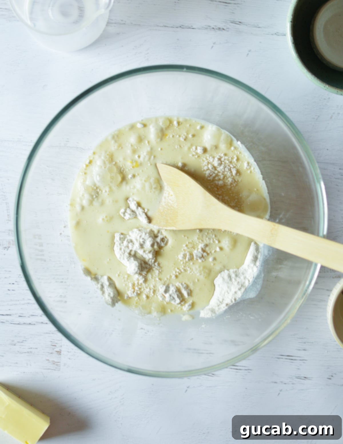 A mixing bowl containing all-purpose flour, whole milk, and egg, in the process of being combined to form pancake batter.