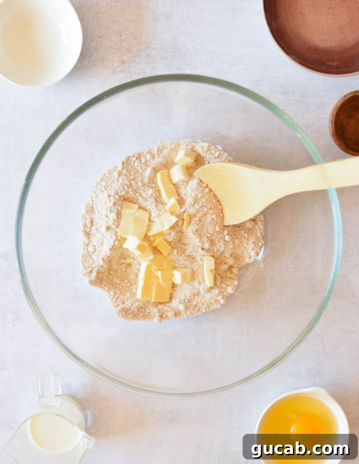 Close-up of oat flour mixed with small, cold pieces of butter, showing the ideal crumbly texture achieved before adding liquid.