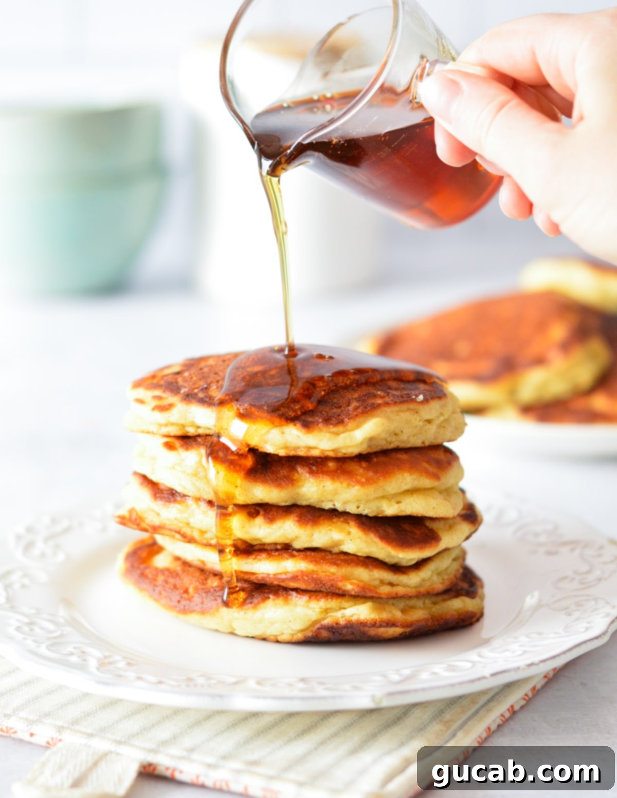 Fluffy Honey Pancakes 2 pouring syrup onto a stack of pancakes.