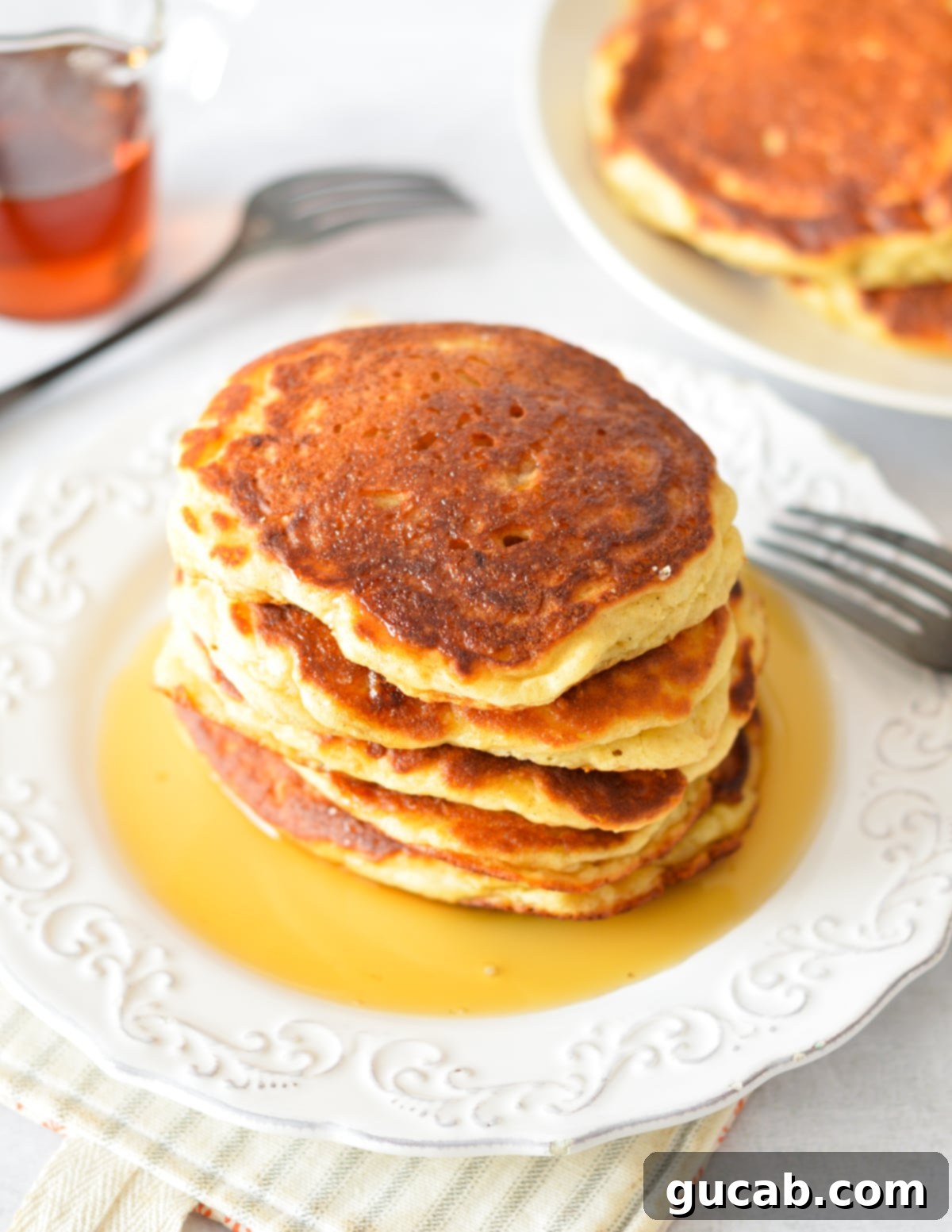 Fluffy Honey Pancakes 11 stack of pancakes on a plate with maple syrup.