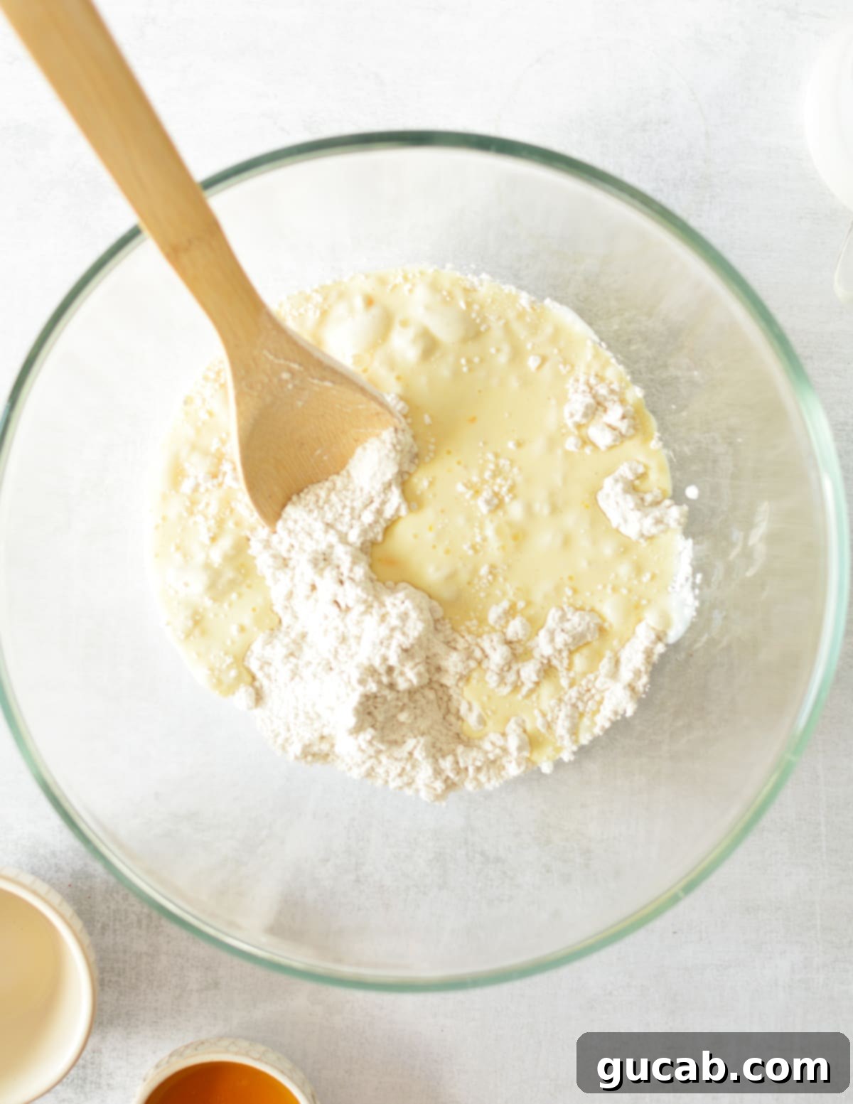 Fluffy Honey Pancakes 5 a bowl of flour with buttermilk and egg on top with a wooden spoon.
