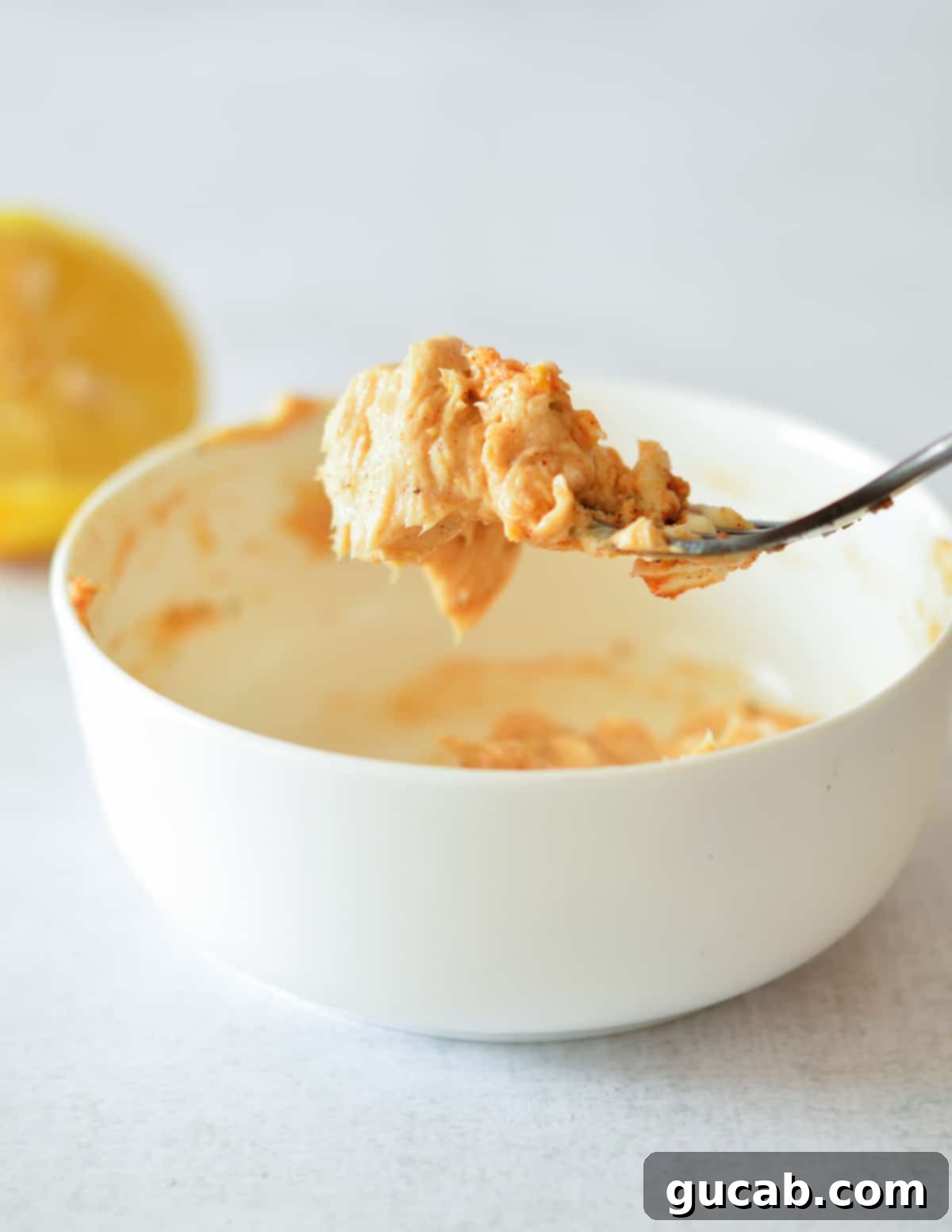 A forkful of freshly mixed Cajun butter, showing its vibrant color and texture, over a bowl.