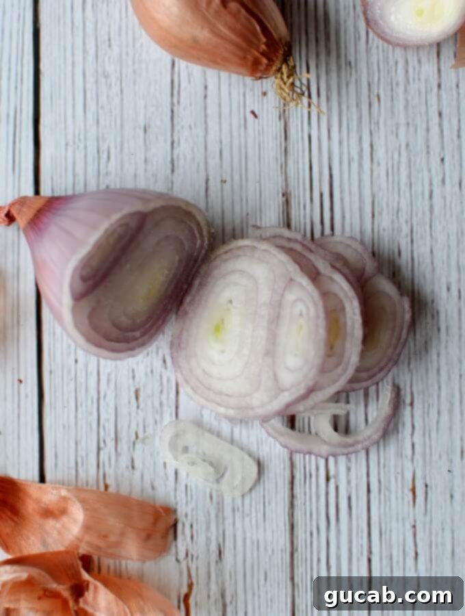 Thinly sliced shallots forming delicate rings, placed inside a glass mason jar, meticulously arranged and ready for the hot pickling brine.