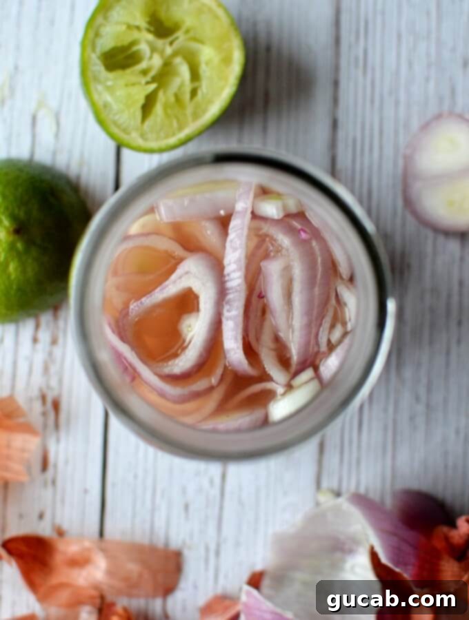 A sealed mason jar filled with vibrant pink quick pickled shallots, glistening in the brine, ready for the refrigerator or serving.