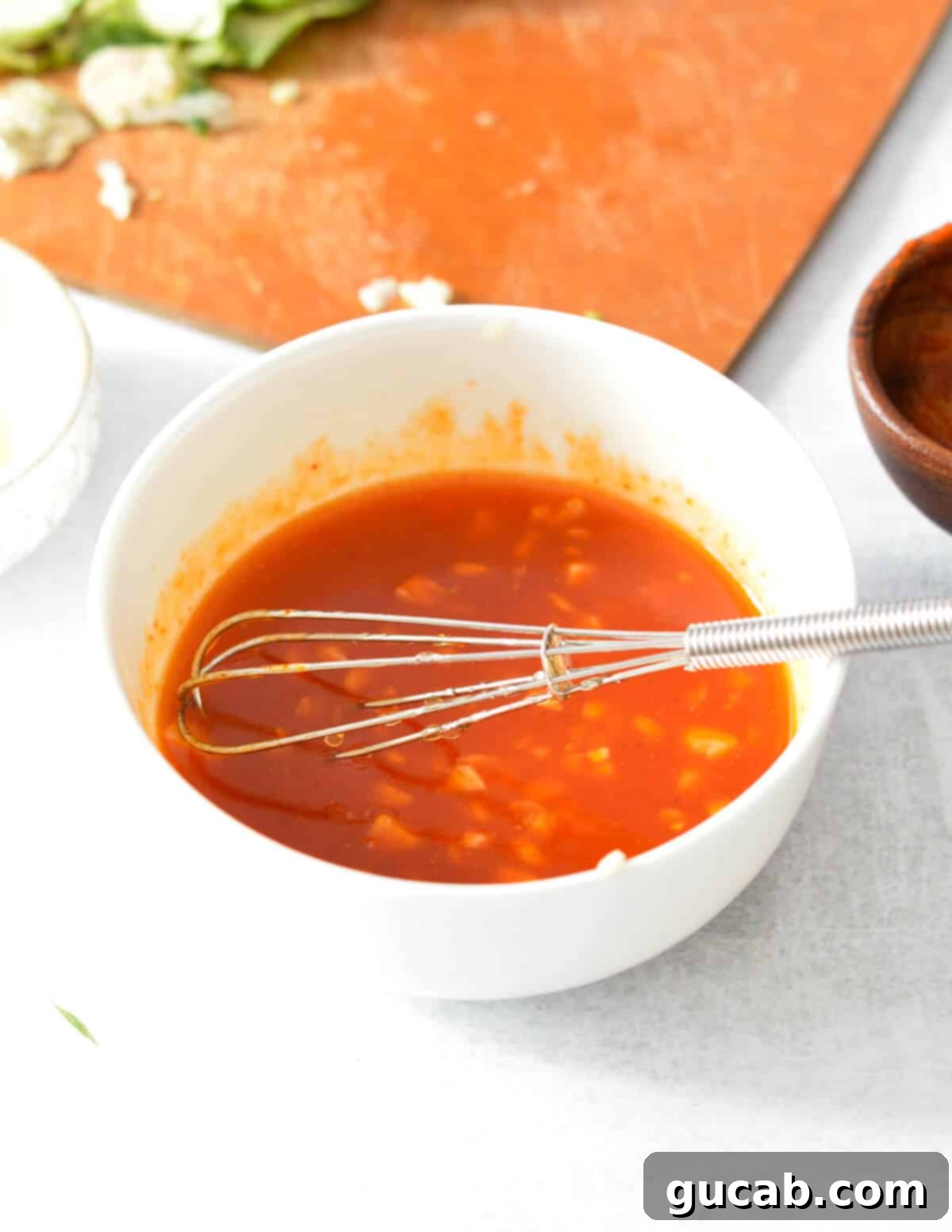 A small bowl of glistening honey sriracha sauce, beautifully blended and ready to be added to the cooked brussels sprouts.