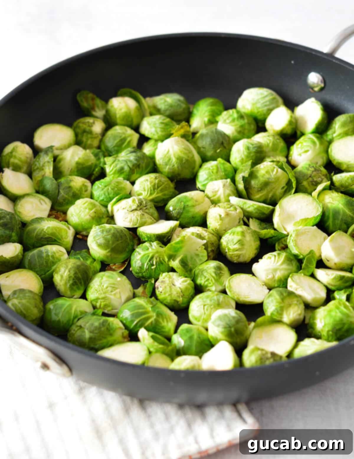 Brussels sprouts sizzling in a hot skillet, beginning to caramelize and turn golden brown.