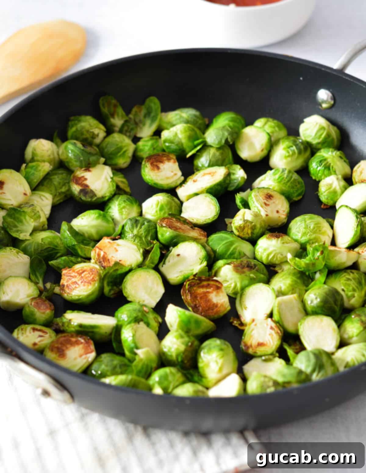 Perfectly caramelized brussels sprouts, showing off their deep golden-brown char, cooking in a skillet.