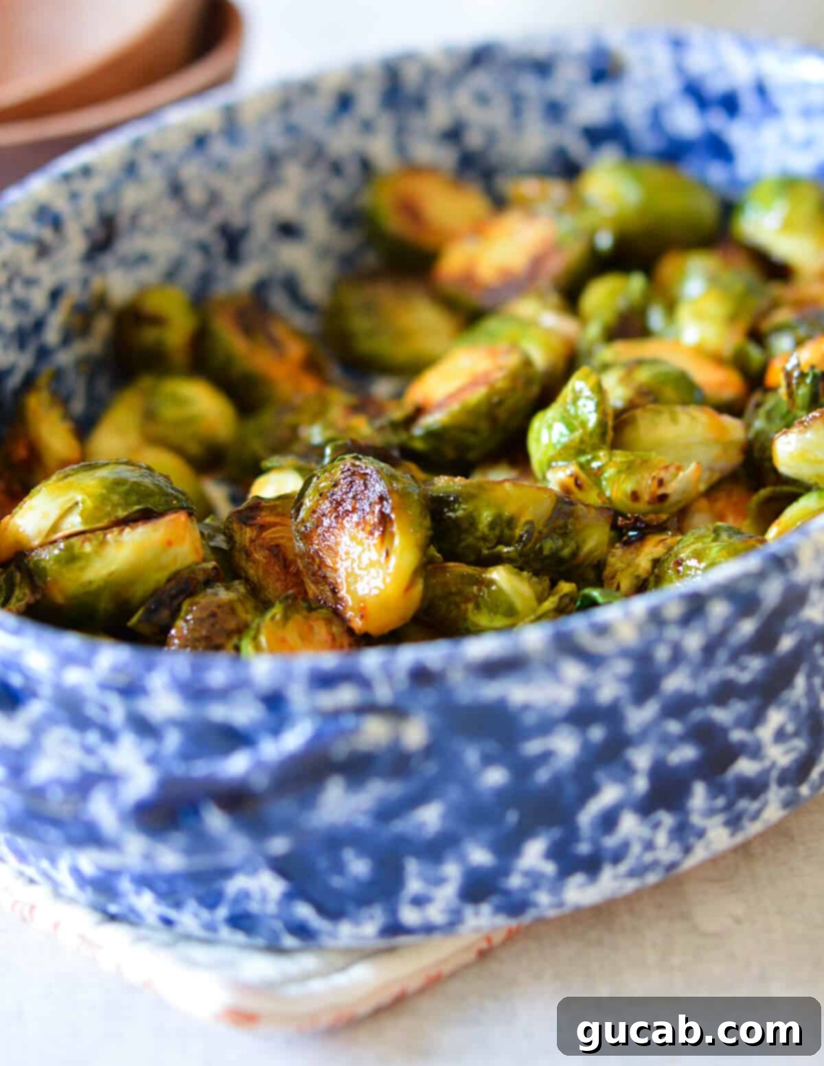 A close-up photo emphasizing the sticky glaze and perfect caramelization of honey sriracha brussels sprouts.