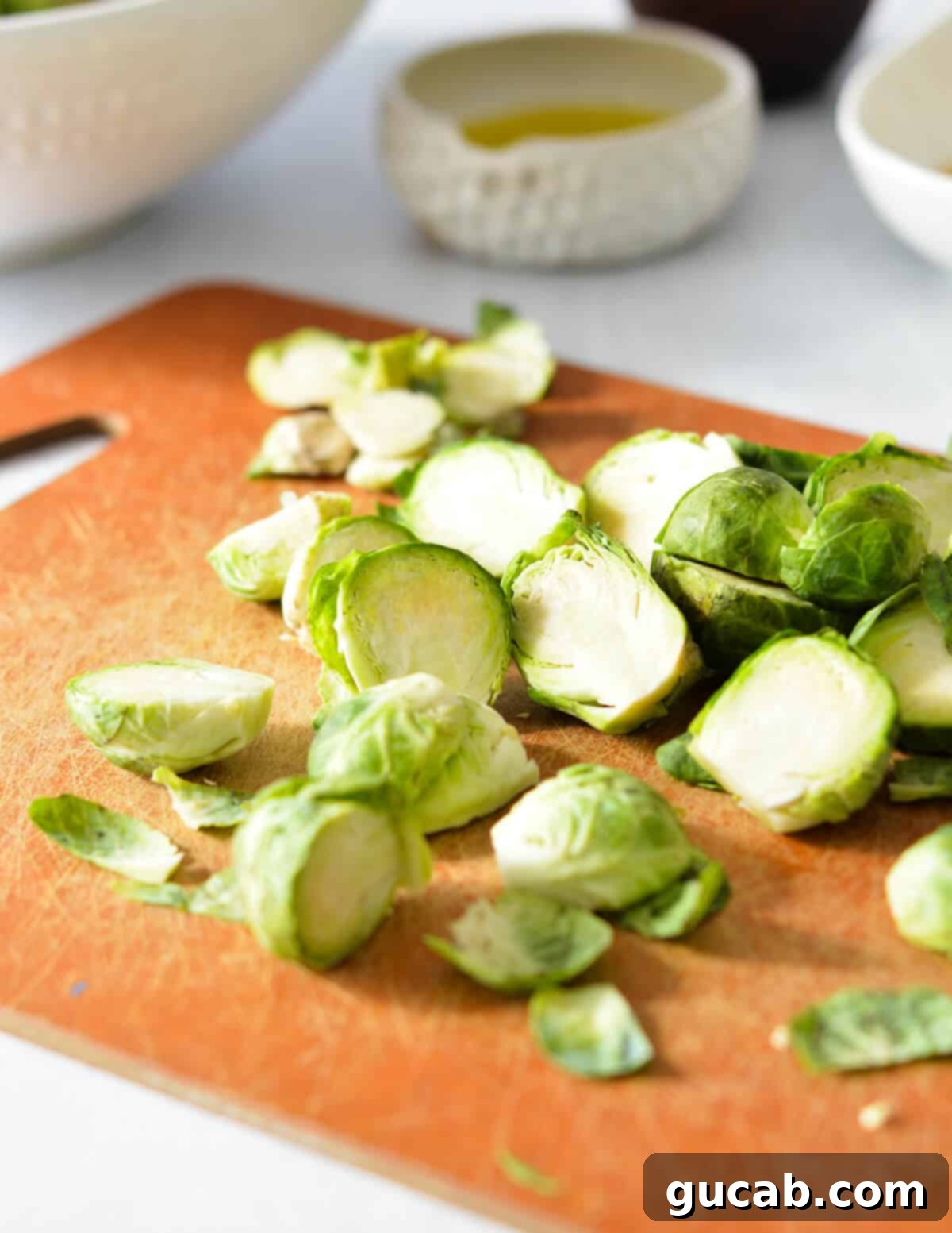 Several neatly cut brussels sprouts, halved and ready for cooking, arranged on a wooden cutting board.