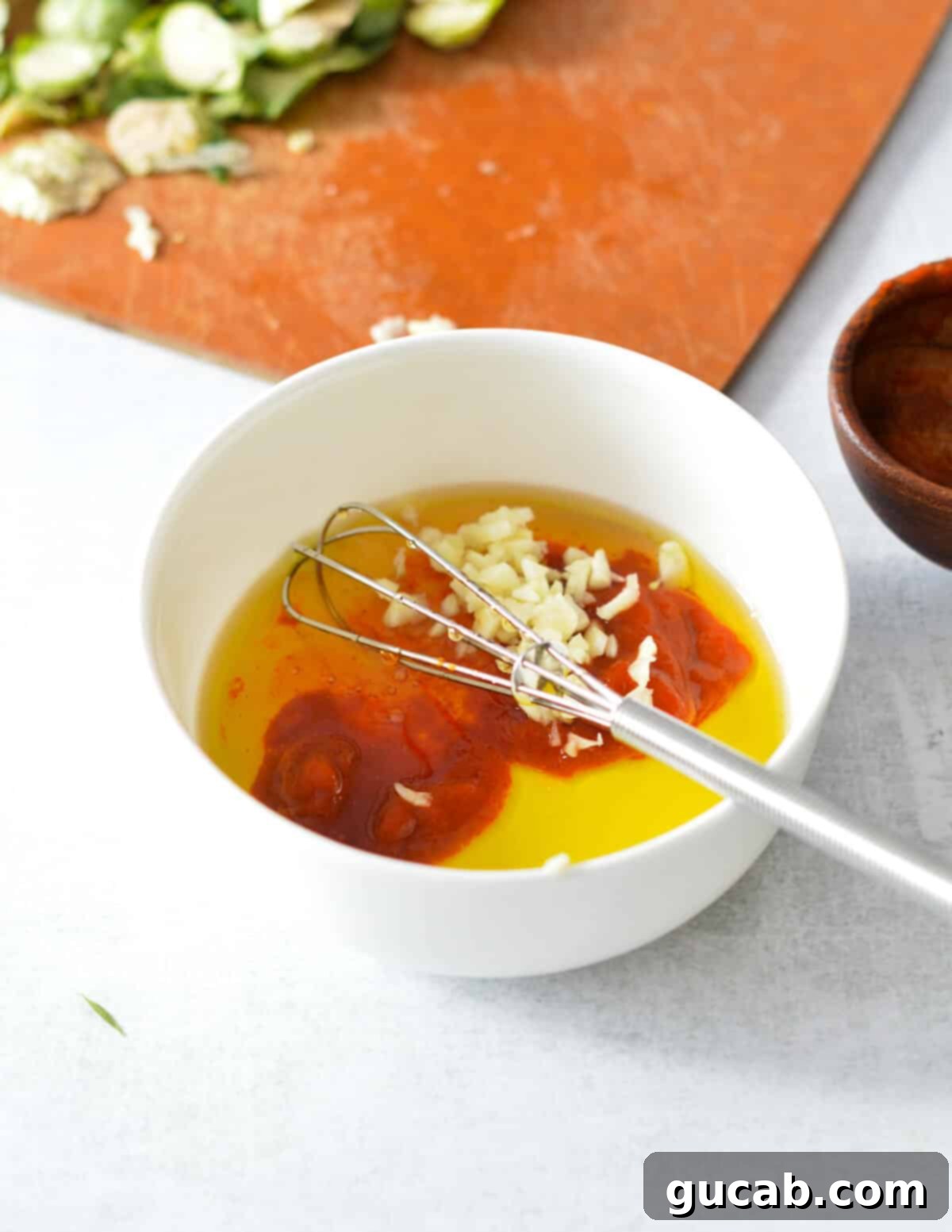 A close-up shot of a bowl containing sriracha, minced garlic, and honey, perfectly mixed for the vibrant sauce.