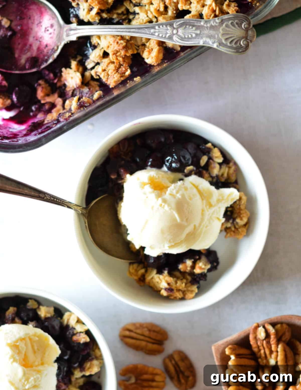 A bowl of healthy blueberry crisp elegantly topped with a generous scoop of creamy vanilla ice cream, creating a perfect dessert.
