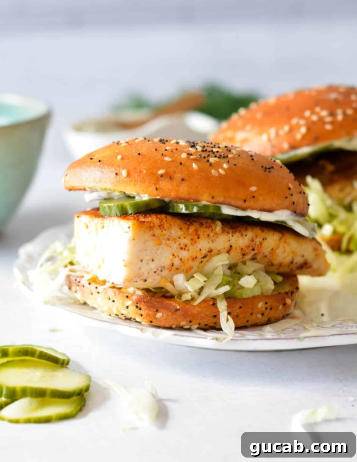 A delicious blackened mahi mahi sandwich with crisp lettuce and homemade pickles on a brioche bun.