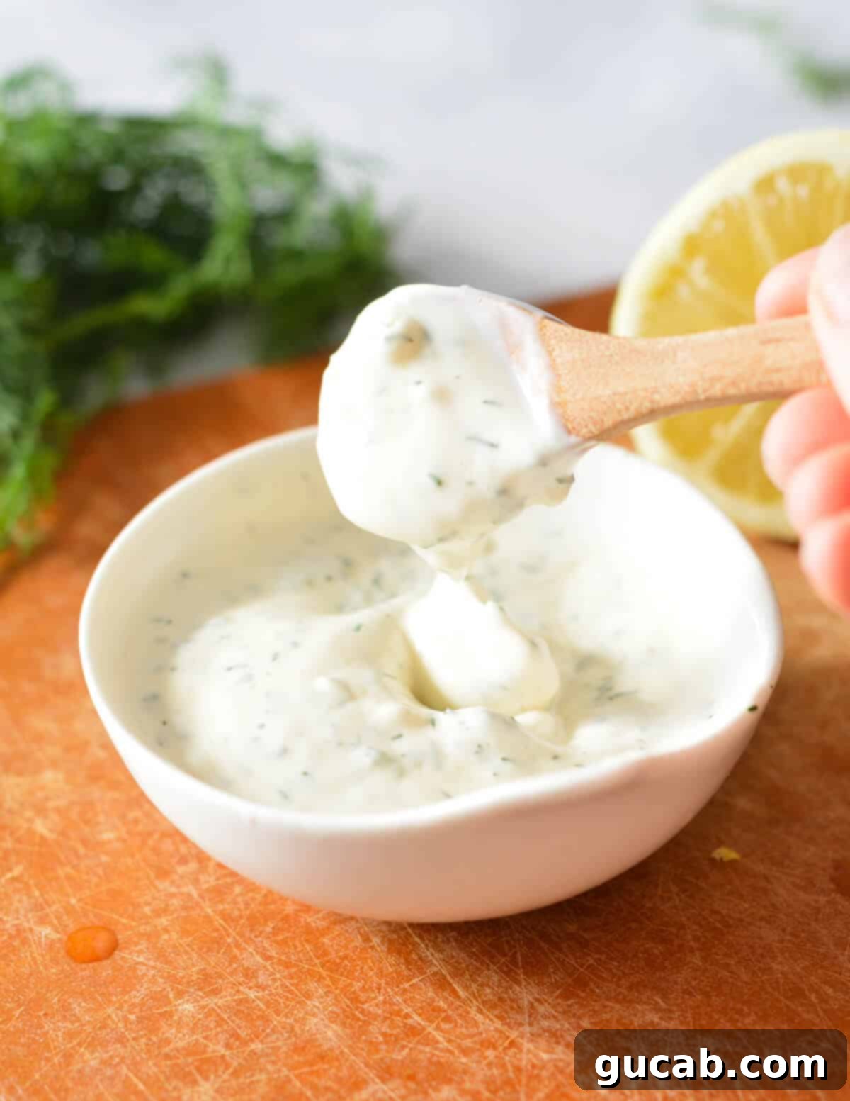 A spoonful of freshly made lemon aioli, showing its creamy texture and specks of dill.